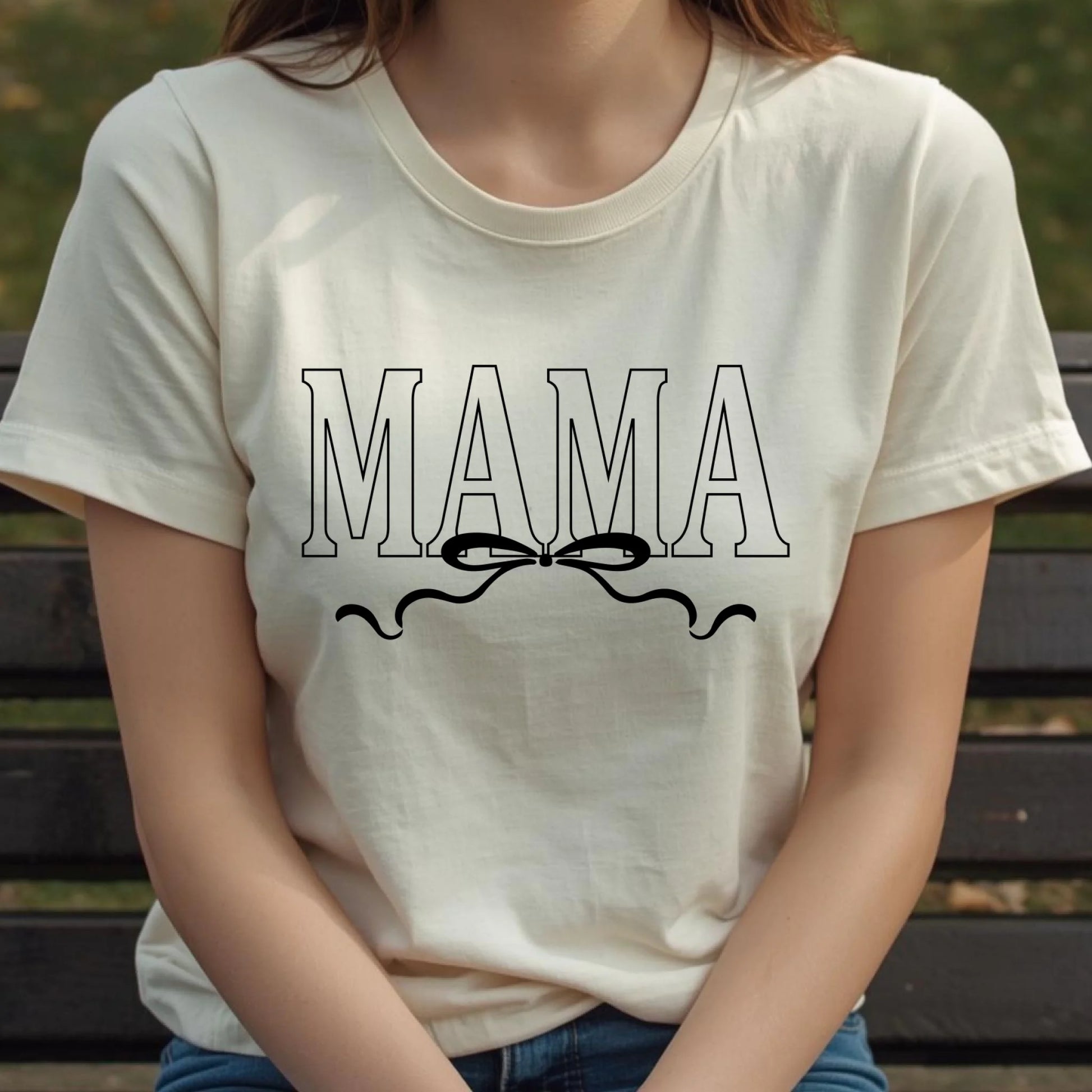 Person wearing a white t-shirt with 'MAMA' text and a bow graphic.