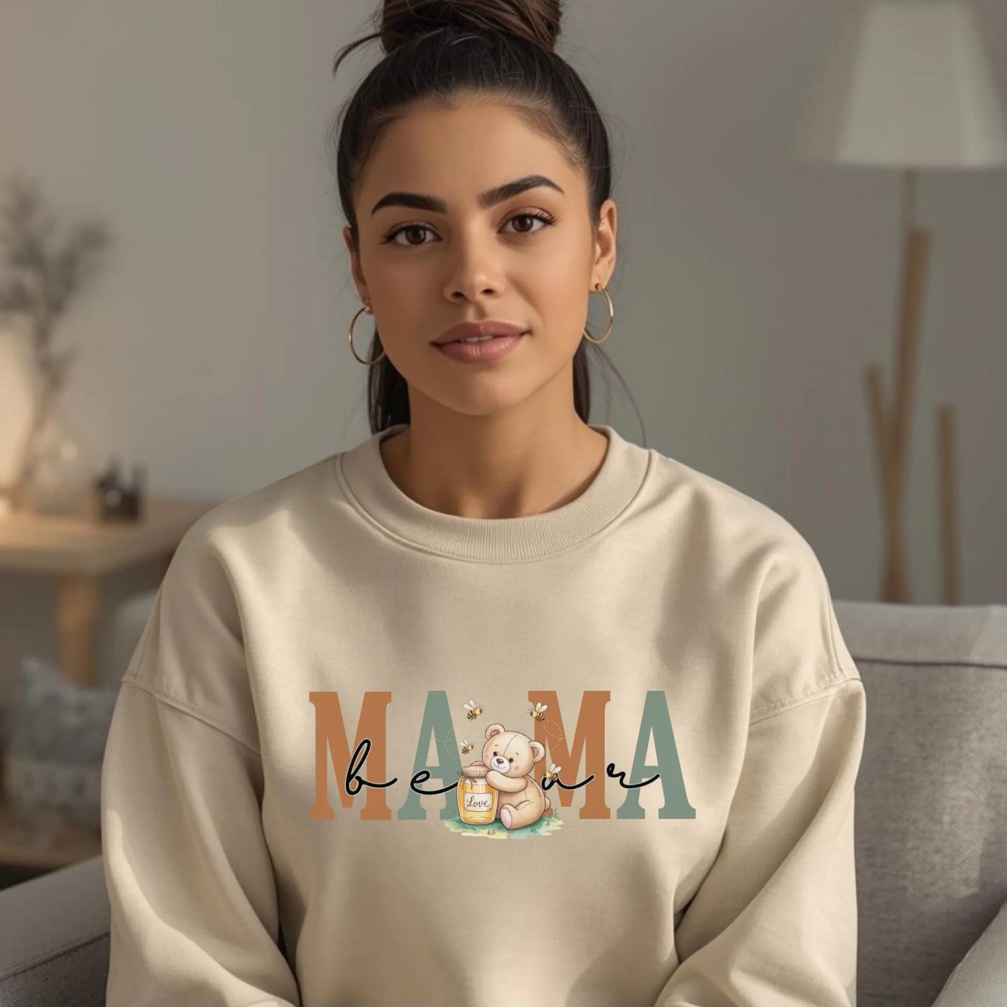 Model wearing a cream-colored personalized mama crewneck featuring a honey bear illustration and soft neutral lettering.