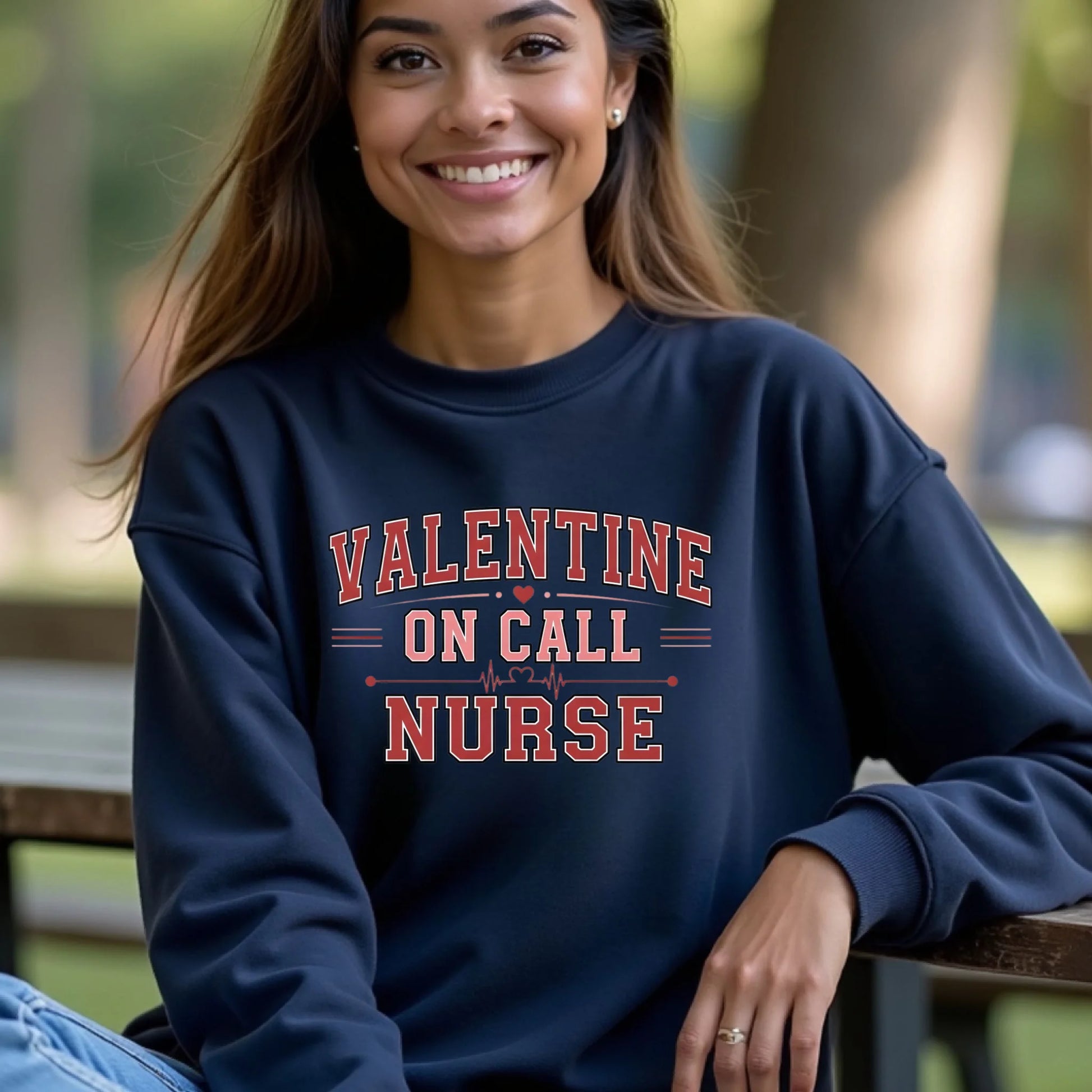 Woman wearing a navy Valentine On Call Nurse crewneck sweatshirt seated outdoors, highlighting a cozy fit and bold nurse graphic.