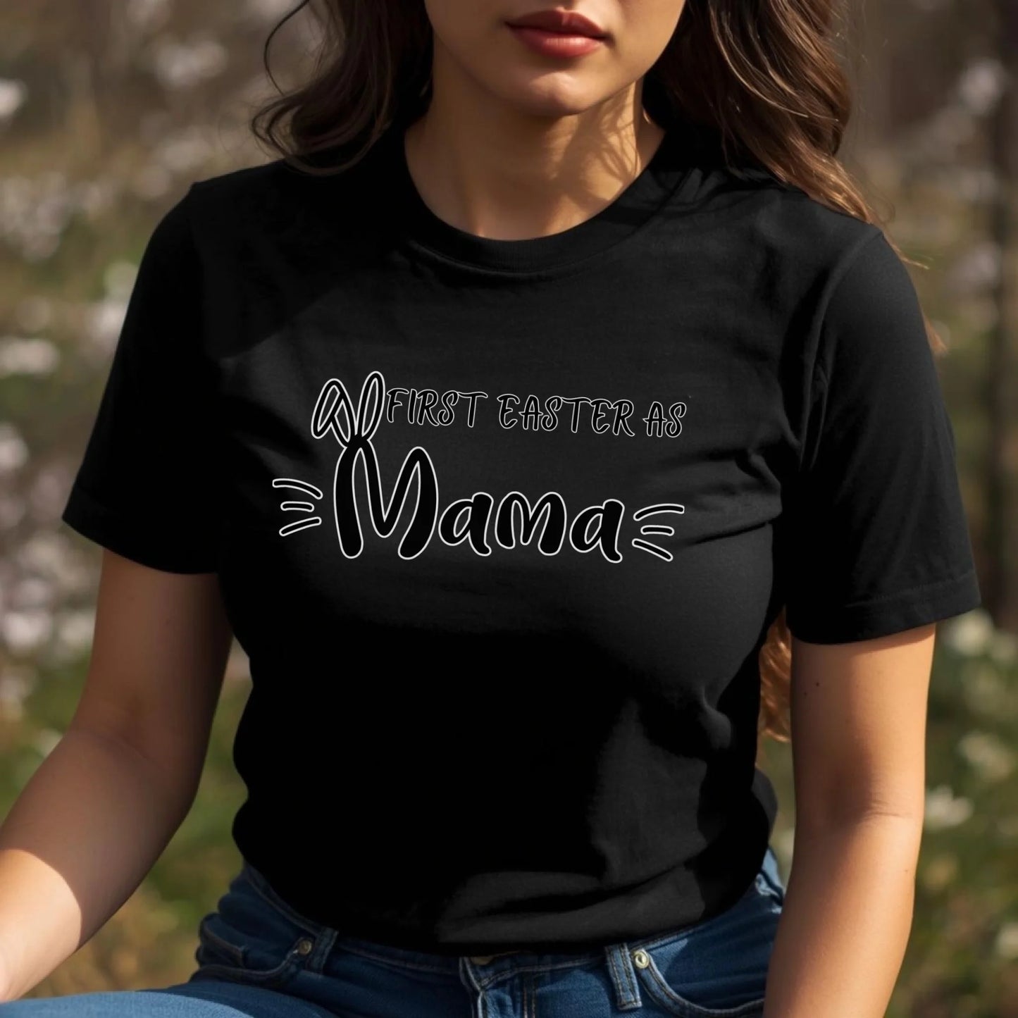 Adult woman modeling a black Bella Canvas t-shirt featuring the “First Easter as Mama” design with bunny ear lettering and playful accents.