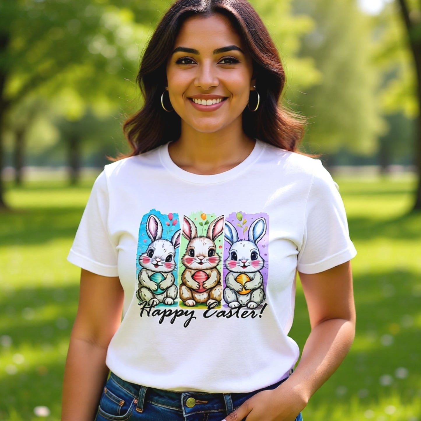 Woman wearing a white Bella Canvas t-shirt featuring a three-panel bunny illustration with “Happy Easter” text, photographed outdoors in a spring setting.