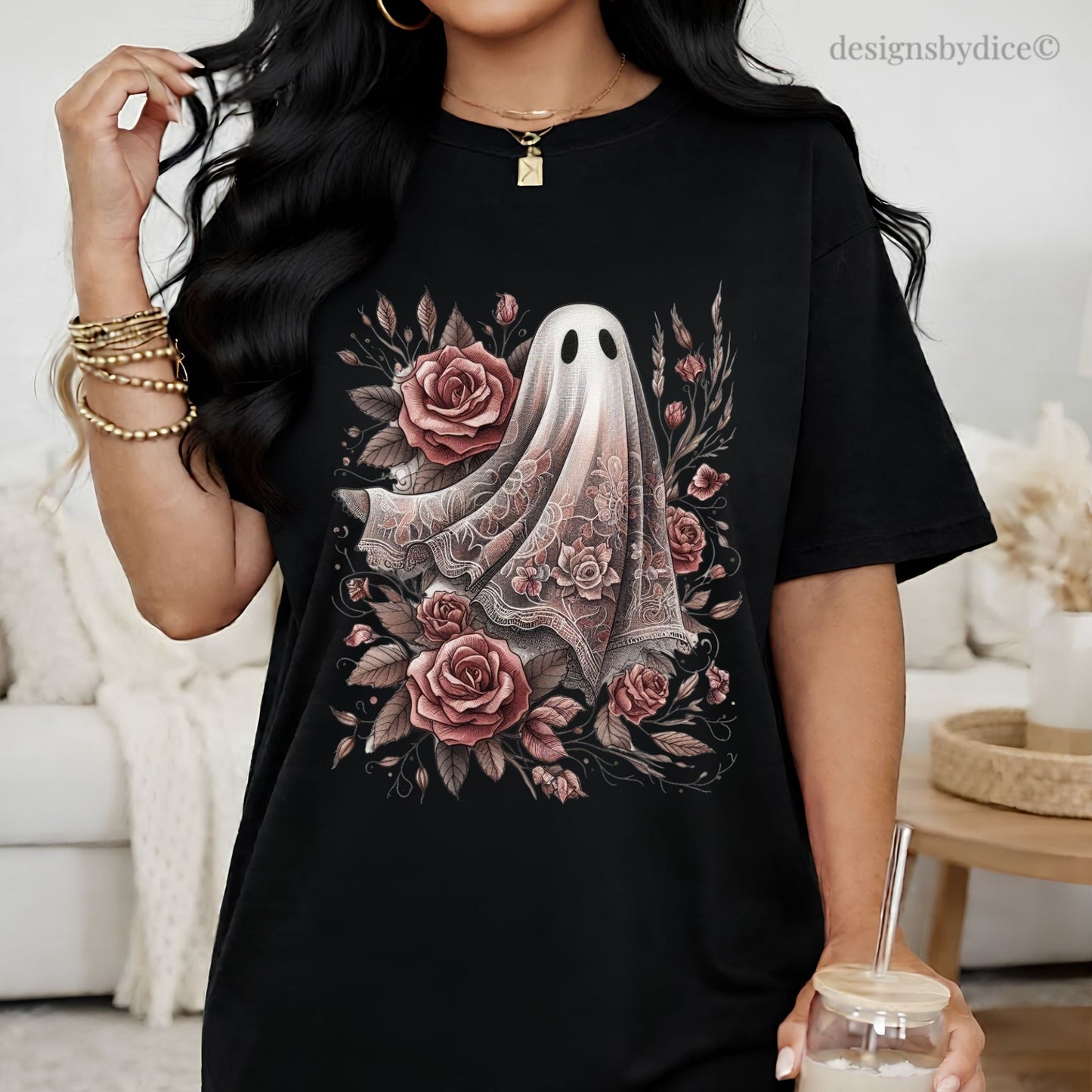 Person wearing a black t-shirt with a ghost and floral design, holding a drink.