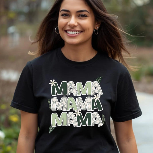Woman smiling outdoors wearing a black “Mama” floral letter t-shirt styled casually in natural lighting