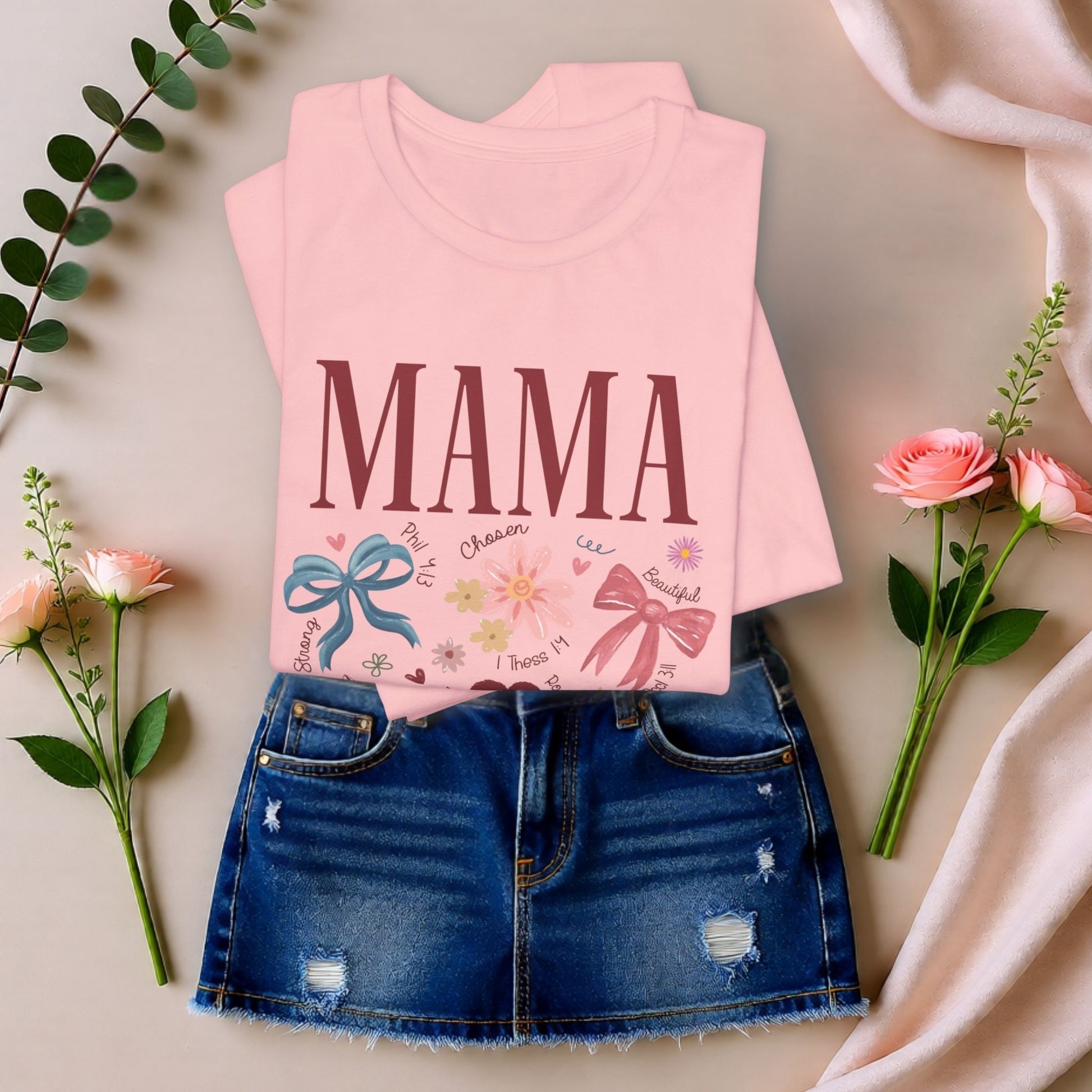 Pink Mama floral t-shirt styled in a soft flat lay with greenery, highlighting a thoughtful and feminine Mother’s Day gift idea.