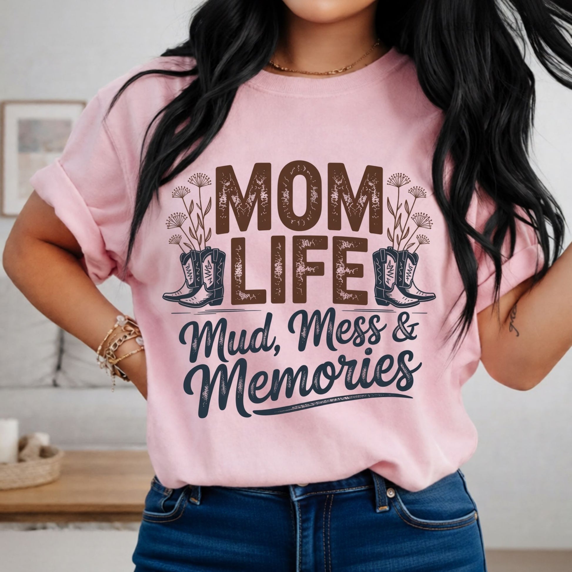 Person wearing a pink t-shirt with 'Mom Life: Mud, Mess & Memories' text and boot graphics.