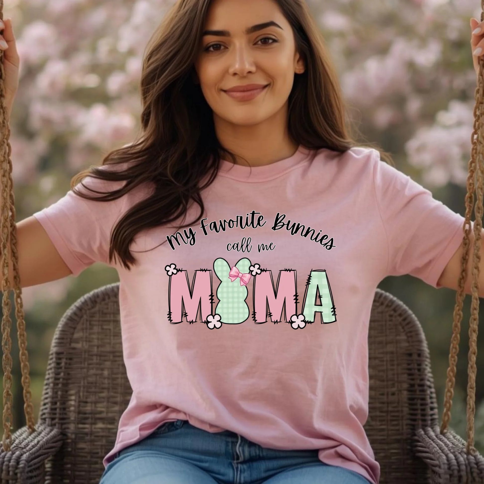 Woman wearing a pink Bella Canvas t-shirt featuring a “My Favorite Bunnies Call Me Mama” Easter bunny design with soft spring colors, photographed outdoors in a relaxed lifestyle setting.