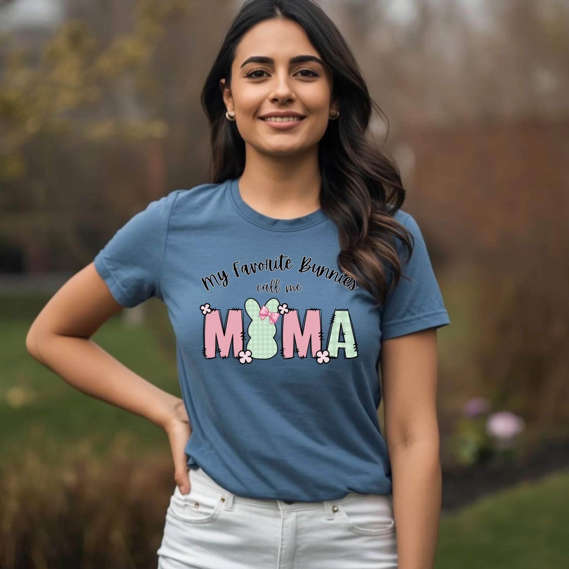 Lifestyle image of a woman wearing a heather blue Bella Canvas t-shirt featuring a spring Easter bunny Mama graphic.