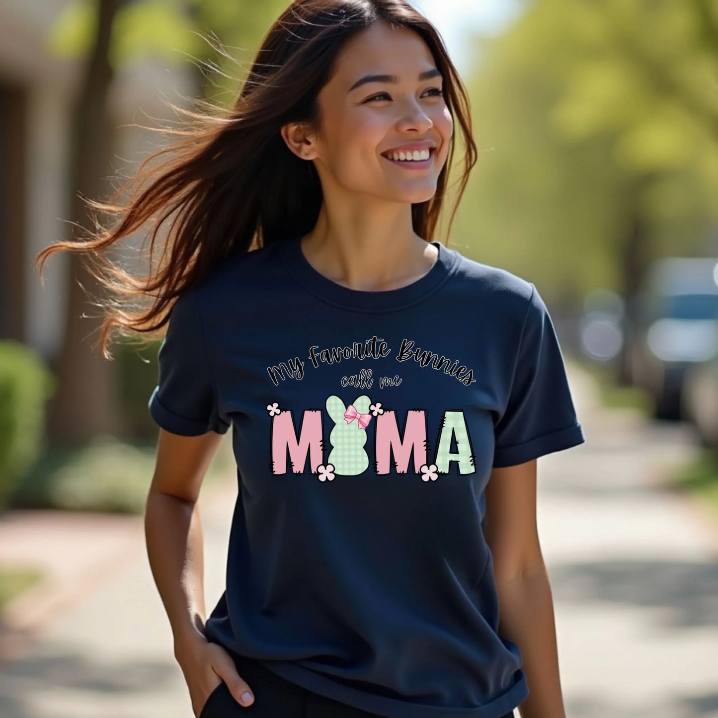 Model walking outdoors wearing a navy Bella Canvas t-shirt with a “My Favorite Bunnies Call Me Mama” Easter bunny graphic, casual spring lifestyle photo.