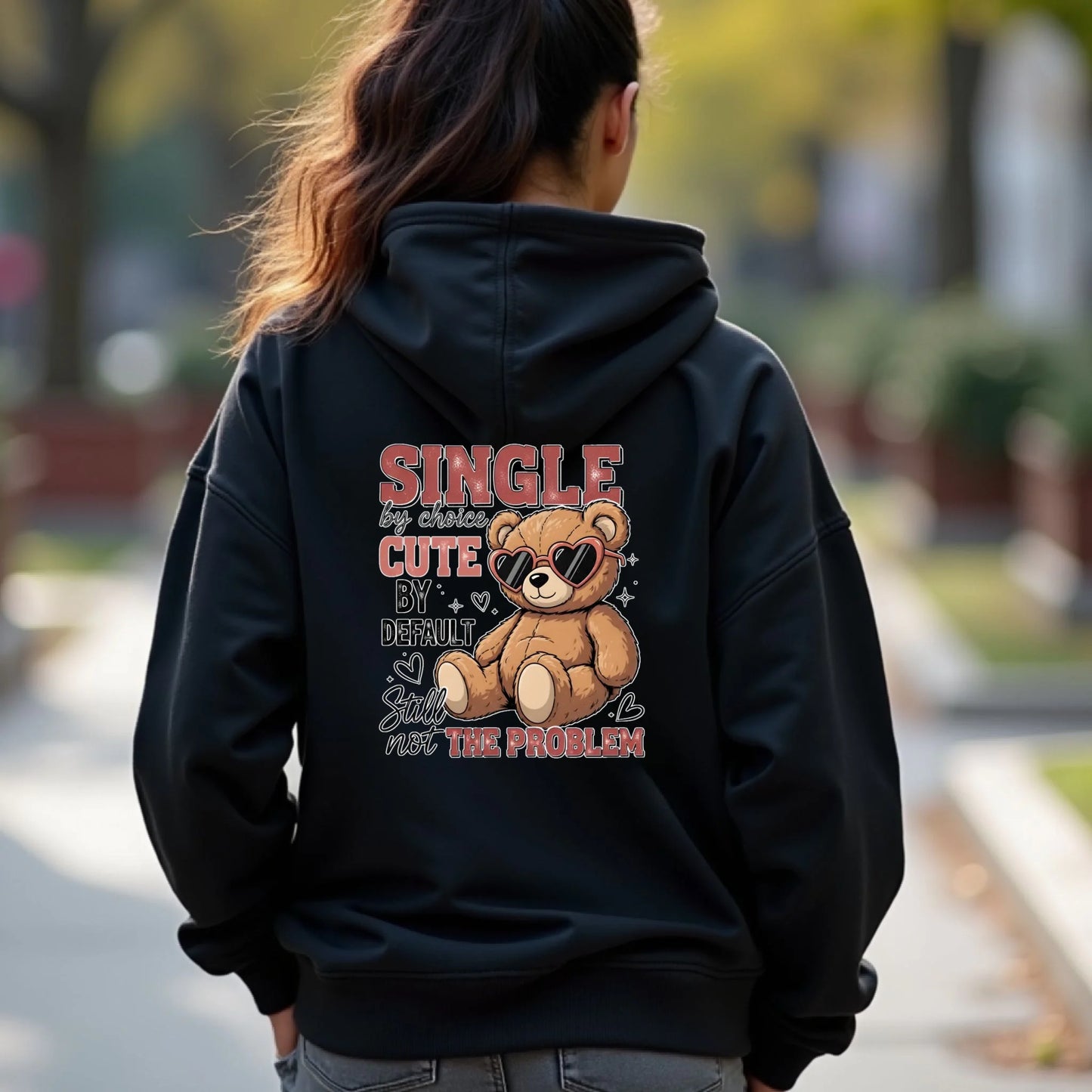 Person wearing a black hoodie with a teddy bear graphic and text on the back, standing outdoors.