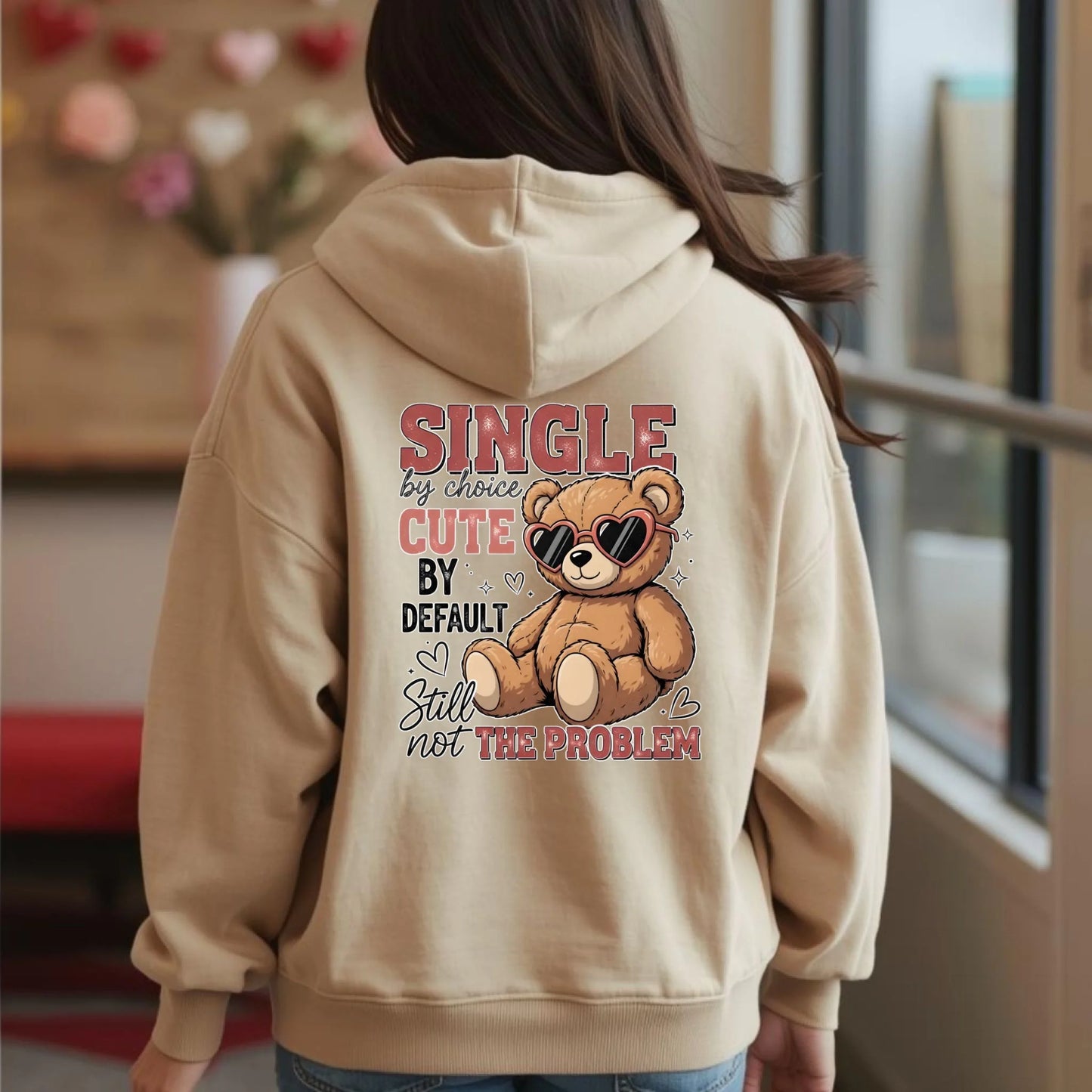 Person wearing a beige hoodie with a teddy bear graphic and text on the back.