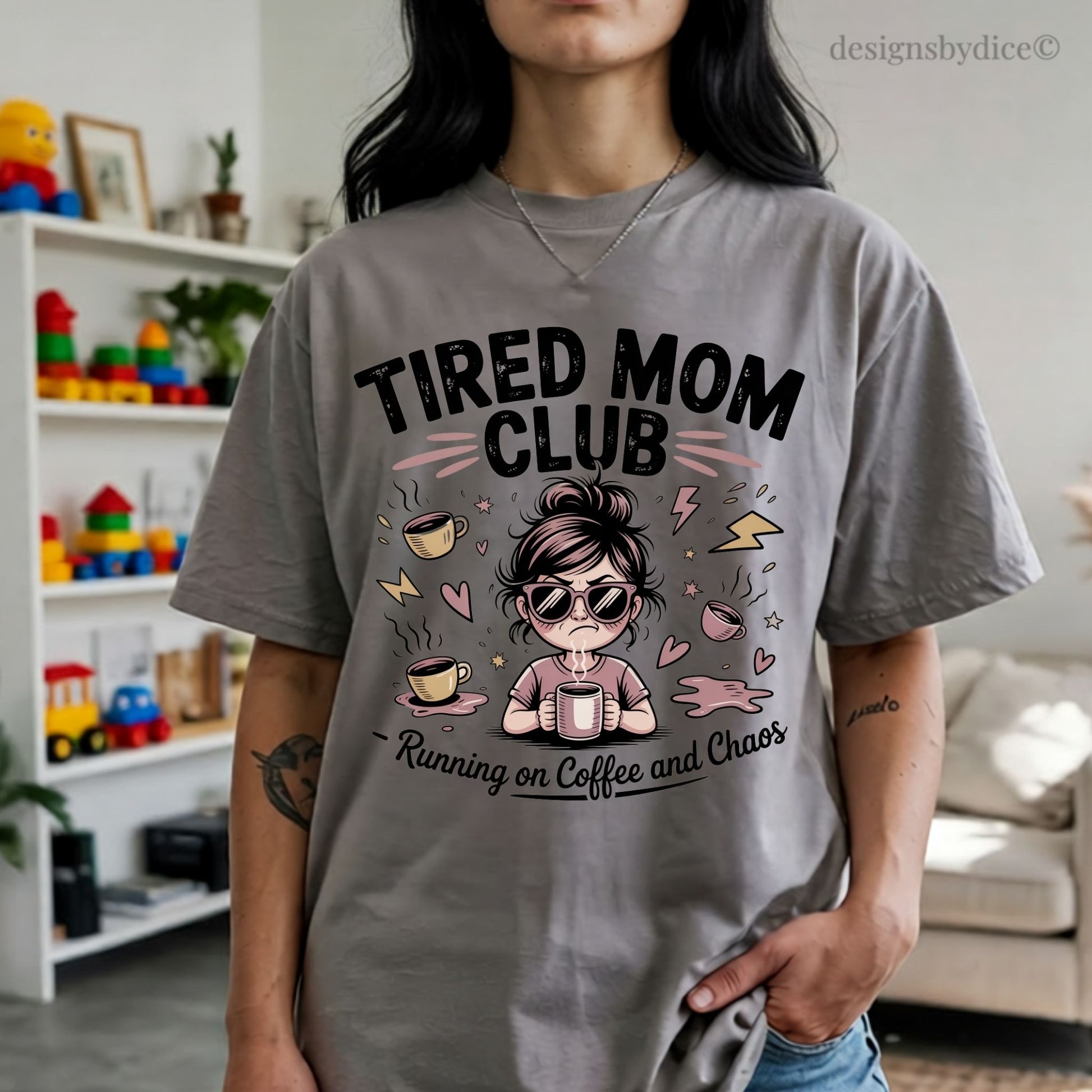 Person wearing a gray t-shirt with 'Tired Mom Club' design in a living room.