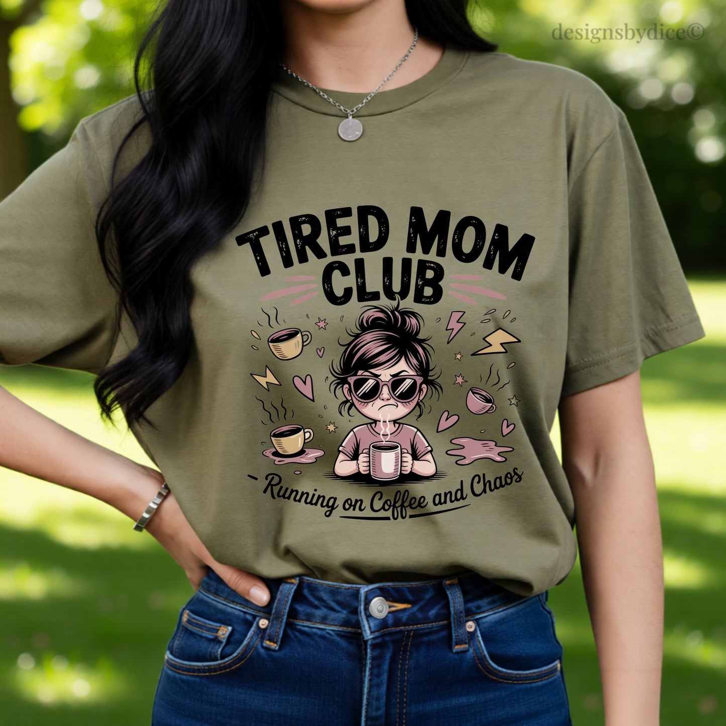 Person wearing a hemp colored t-shirt with 'TIRED MOM CLUB' design outdoors.