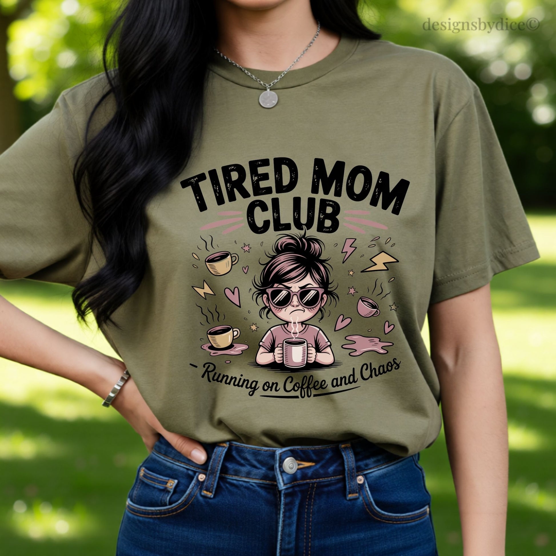 Person wearing a hemp colored t-shirt with 'TIRED MOM CLUB' design outdoors.
