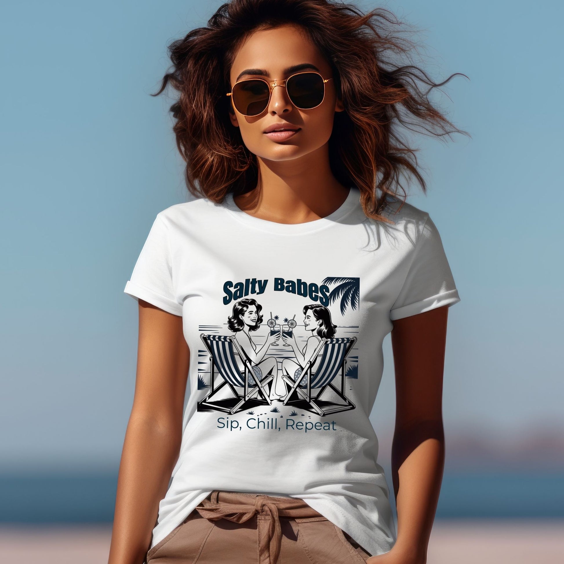 Woman wearing a white t-shirt with 'Salty Babes' design on a beach.